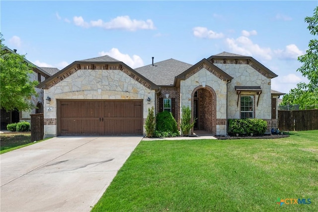french country style house with fence, a garage, stone siding, a front lawn, and concrete driveway