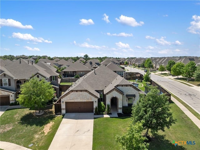 view of front facade featuring a residential view, stone siding, a front lawn, concrete driveway, and an attached garage