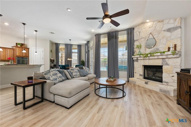 living room with recessed lighting, ceiling fan, a fireplace, baseboards, and light wood-type flooring