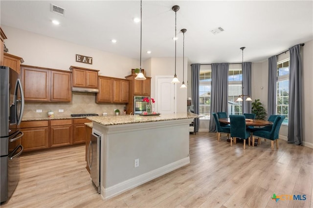 kitchen with under cabinet range hood, visible vents, appliances with stainless steel finishes, and brown cabinetry