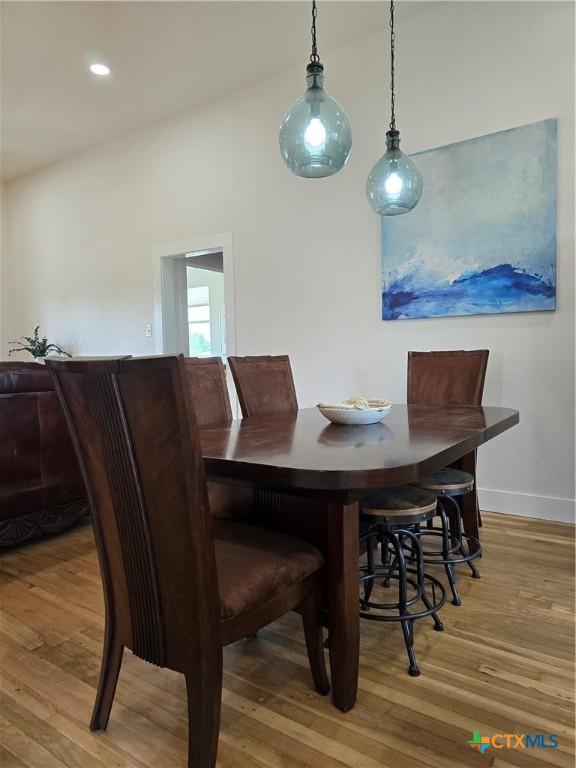 kitchen featuring stainless steel appliances, hanging light fixtures, wooden counters, light wood-style floors, and white cabinets