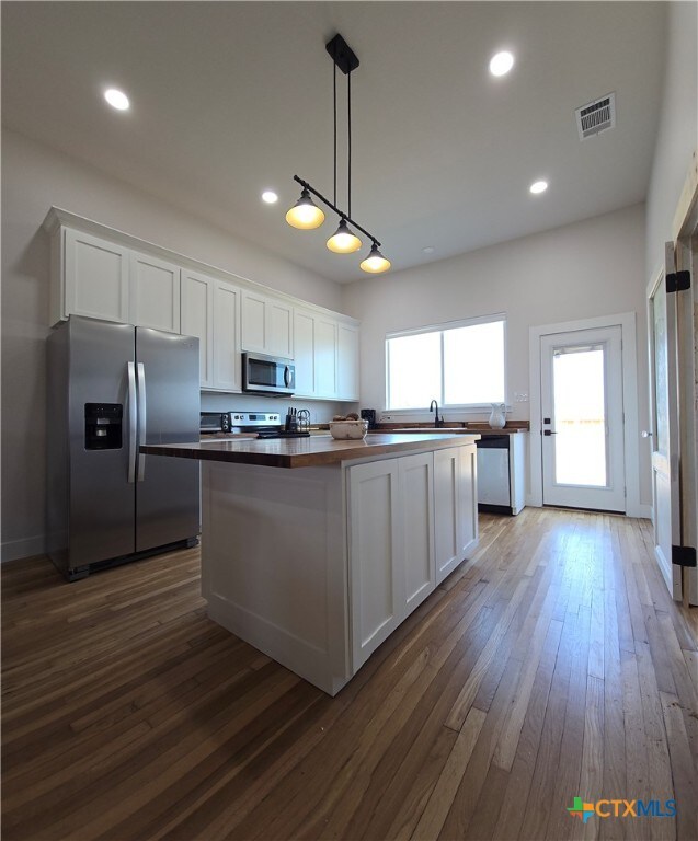 kitchen featuring white cabinets, visible vents, stainless steel appliances, and pendant lighting