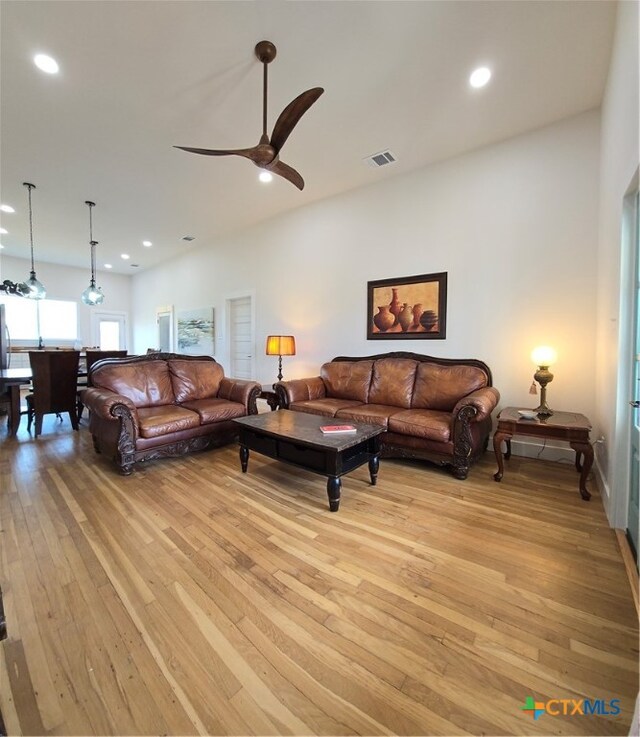 living area featuring light wood-style flooring, a ceiling fan, visible vents, and recessed lighting