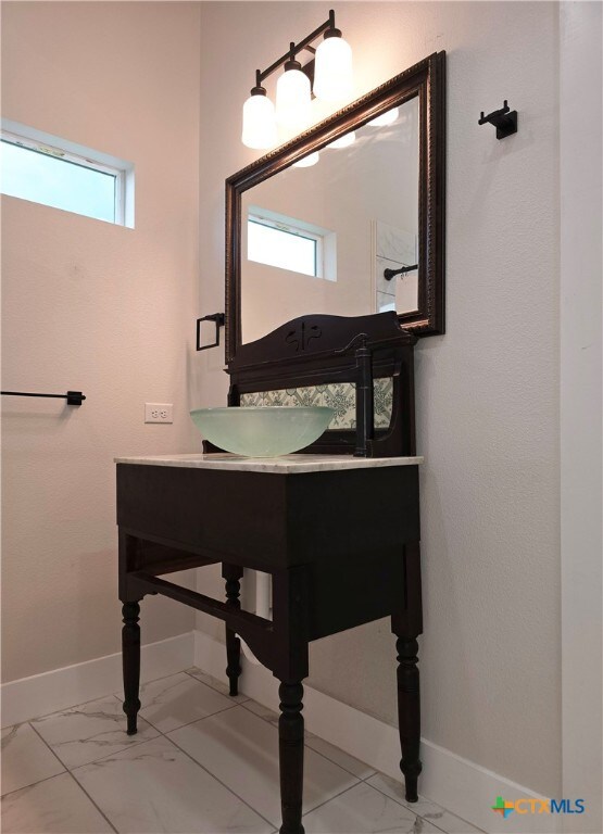 bathroom with marble finish floor, plenty of natural light, baseboards, and vanity