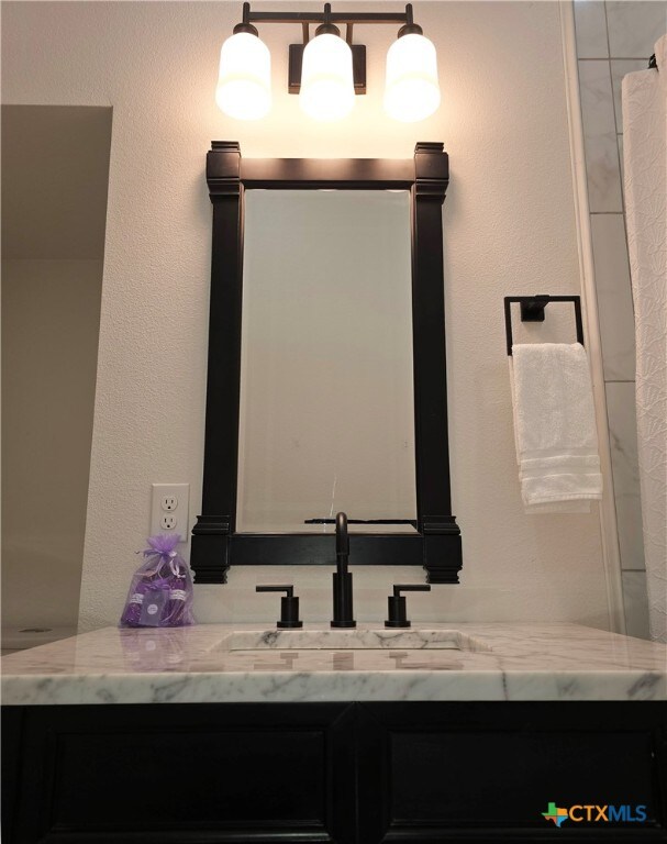 bathroom with a textured wall and vanity