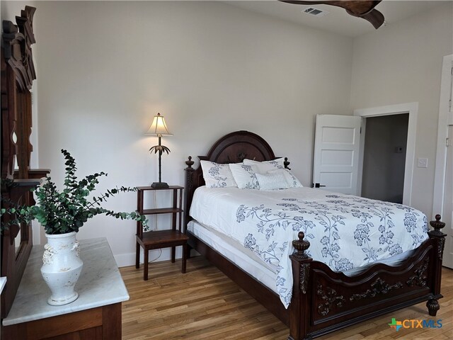 bedroom with baseboards, visible vents, and wood finished floors