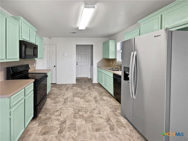 kitchen featuring visible vents, light countertops, stone finish floor, black appliances, and green cabinetry