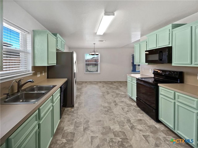 kitchen featuring a chandelier, a sink, black appliances, and green cabinetry