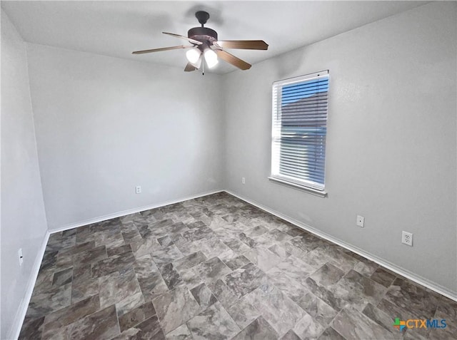 empty room with ceiling fan and baseboards