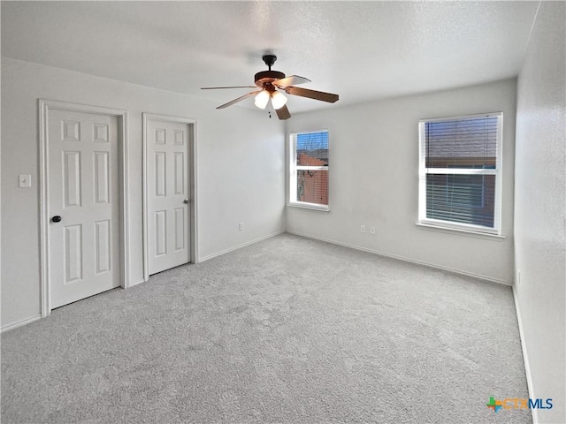 unfurnished bedroom with a ceiling fan, baseboards, carpet floors, and a textured ceiling