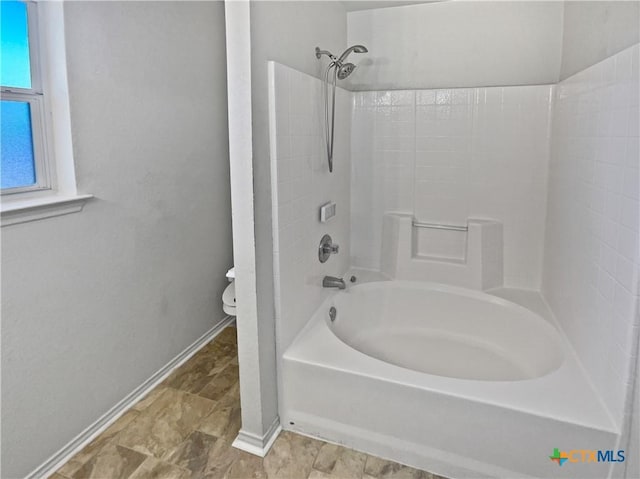 bathroom featuring tub / shower combination, toilet, and baseboards