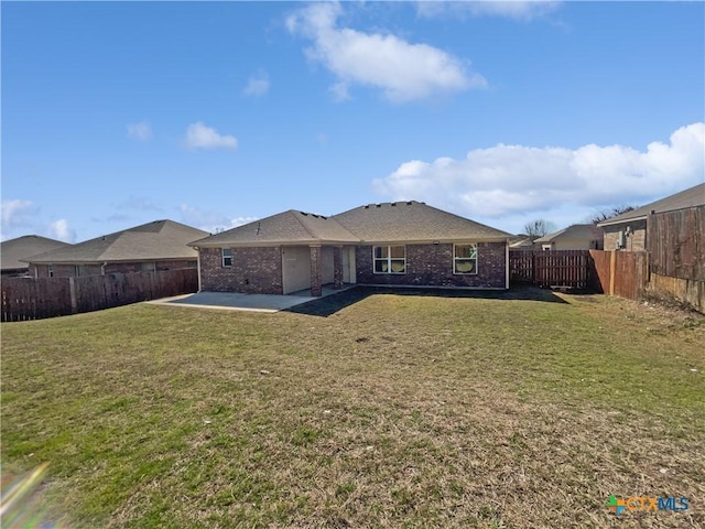 back of property with a patio area, a yard, a fenced backyard, and brick siding