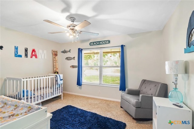 carpeted bedroom with ceiling fan and a nursery area