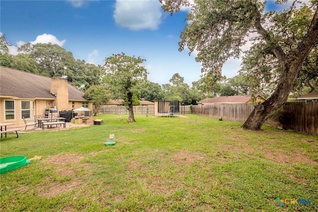 view of yard featuring a trampoline and a patio