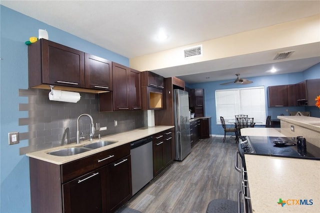 kitchen featuring ceiling fan, sink, stainless steel appliances, backsplash, and hardwood / wood-style flooring