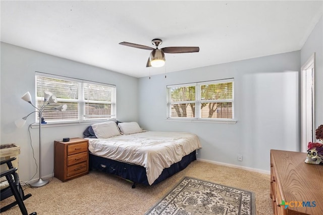 bedroom with ceiling fan, light colored carpet, and multiple windows