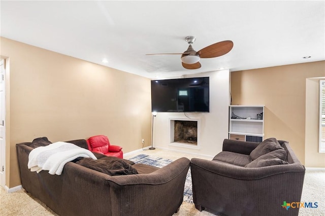 carpeted living room featuring a premium fireplace and ceiling fan