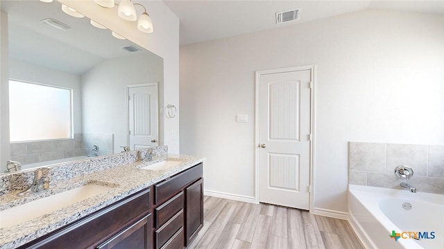 4024 Hayes Ct, Belton, TX 76513 - full bathroom with vaulted ceiling, a garden tub, double vanity, wood finished floors, and baseboards