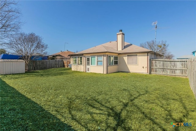 back of house featuring a fenced backyard, a chimney, and a lawn