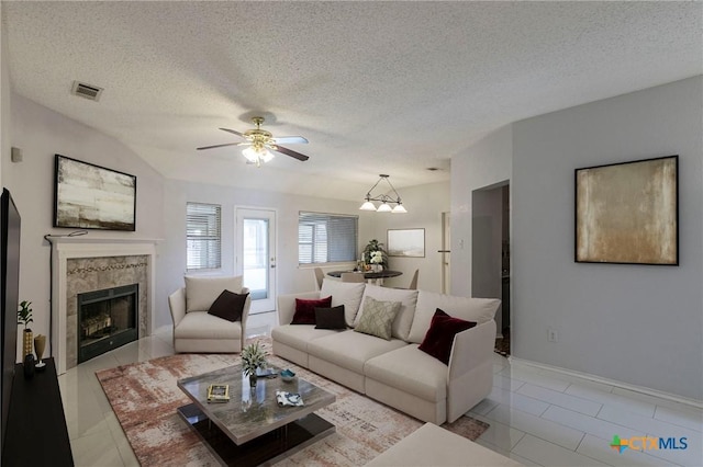 living area featuring light tile patterned floors, a textured ceiling, a premium fireplace, visible vents, and a ceiling fan