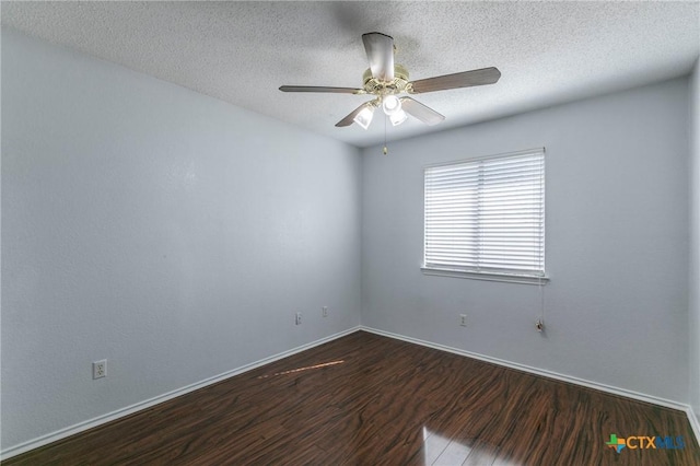 spare room with a textured ceiling, dark wood-type flooring, a ceiling fan, and baseboards