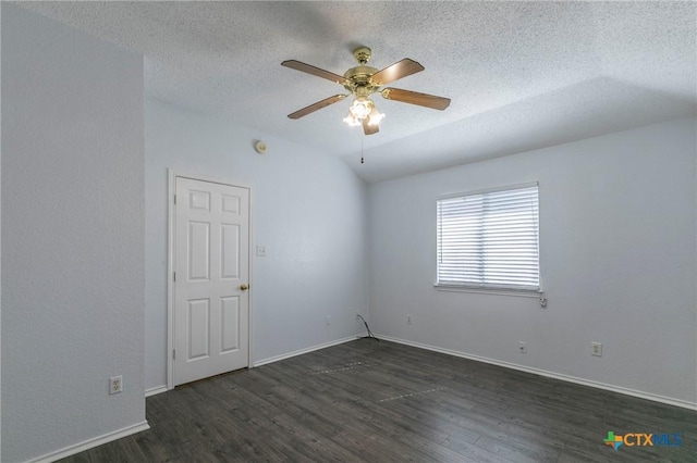 spare room with dark wood finished floors, a ceiling fan, vaulted ceiling, a textured ceiling, and baseboards