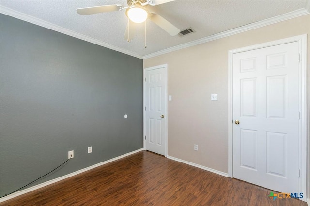 empty room featuring baseboards, visible vents, a ceiling fan, ornamental molding, and wood finished floors