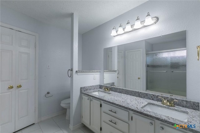 full bathroom featuring toilet, double vanity, an enclosed shower, and a sink