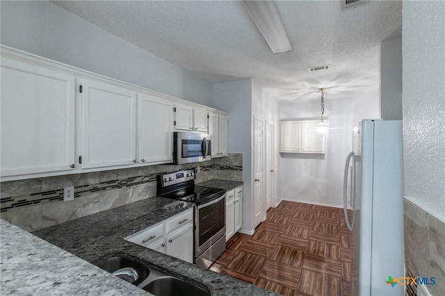 kitchen with a sink, visible vents, white cabinets, appliances with stainless steel finishes, and dark stone countertops