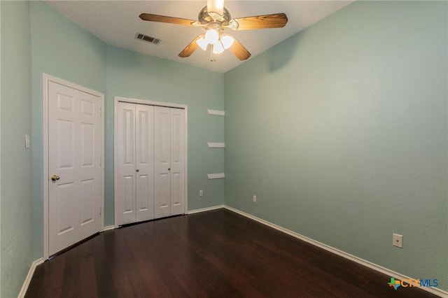 unfurnished bedroom featuring dark wood-type flooring, a closet, visible vents, and baseboards