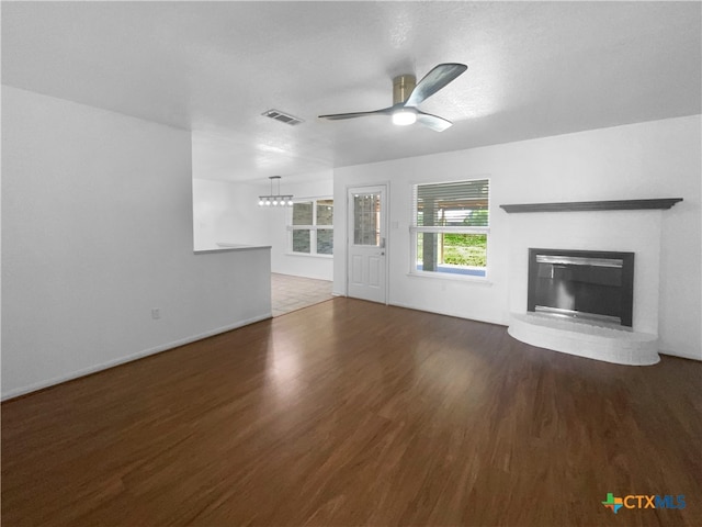 unfurnished living room featuring dark wood-type flooring, ceiling fan, and a brick fireplace