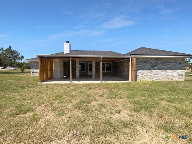 rear view of property with a lawn and a patio