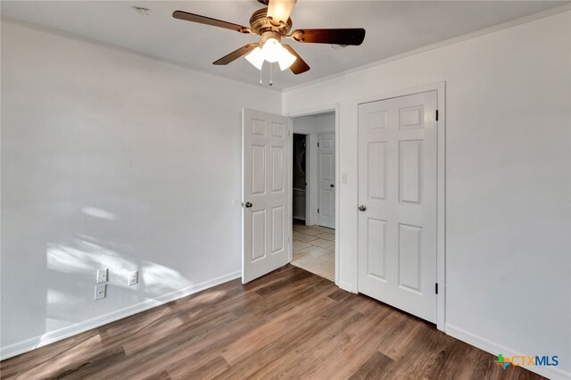 empty room with ornamental molding, wood-type flooring, and ceiling fan