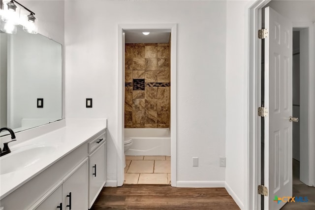 full bathroom featuring hardwood / wood-style floors, vanity, toilet, and tiled shower / bath