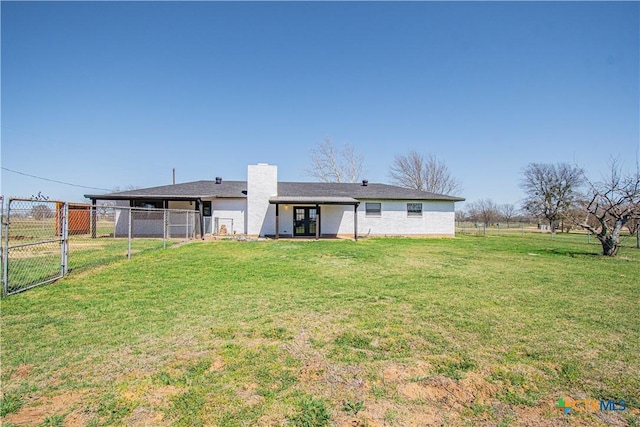 rear view of house featuring fence, a lawn, and a gate