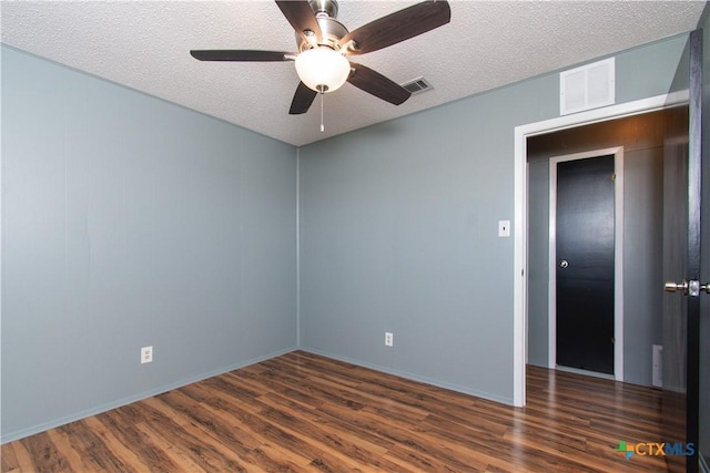 empty room with wood finished floors, visible vents, and a textured ceiling