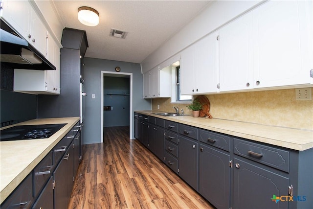 kitchen with a sink, black electric cooktop, visible vents, and white cabinets