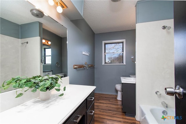 bathroom with baseboards, toilet, vanity, wood finished floors, and a textured ceiling