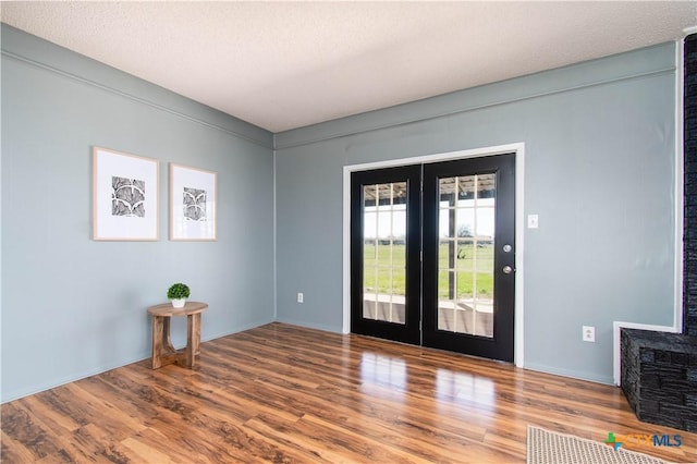 entrance foyer with wood finished floors, french doors, and a textured ceiling