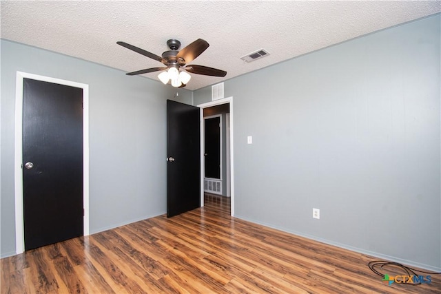 unfurnished bedroom featuring visible vents, a textured ceiling, and wood finished floors