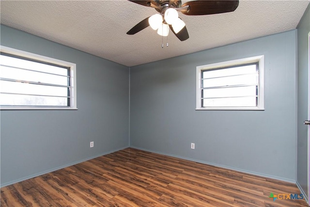 spare room featuring baseboards, a textured ceiling, dark wood-type flooring, and a ceiling fan