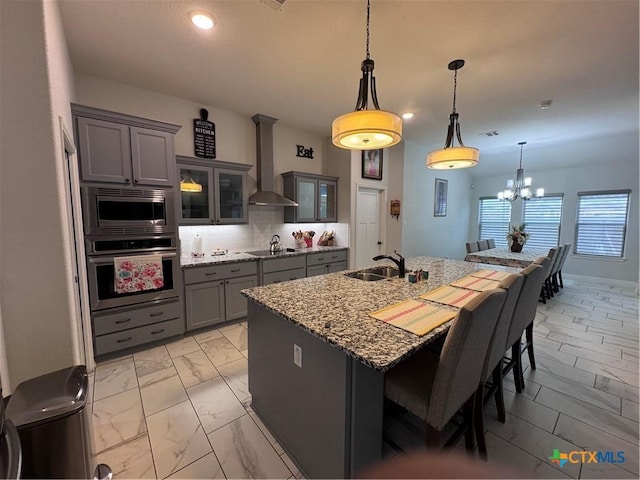 3220 Wild Seed Dr, Salado, TX 76571 - kitchen with marble finish floor, stainless steel appliances, a sink, wall chimney range hood, and gray cabinets
