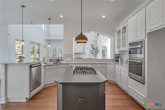 200 Tovas Secret Cv, Georgetown, TX 78628 - kitchen with appliances with stainless steel finishes, a sink, arched walkways, a center island, and glass insert cabinets