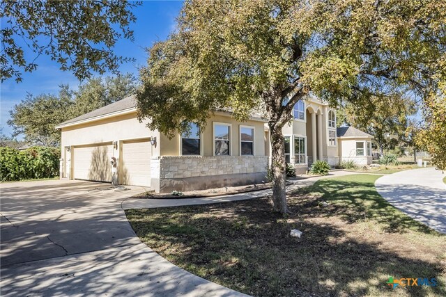 200 Tovas Secret Cv, Georgetown, TX 78628 - obstructed view of property featuring an attached garage, stucco siding, driveway, and stone siding