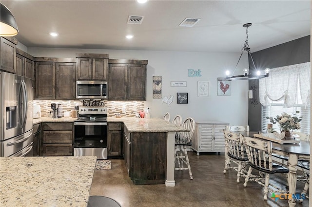 kitchen featuring visible vents, appliances with stainless steel finishes, a peninsula, dark brown cabinets, and backsplash