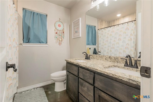 full bath featuring toilet, double vanity, baseboards, and a sink