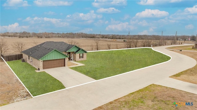 view of property's community with driveway, a rural view, and a yard