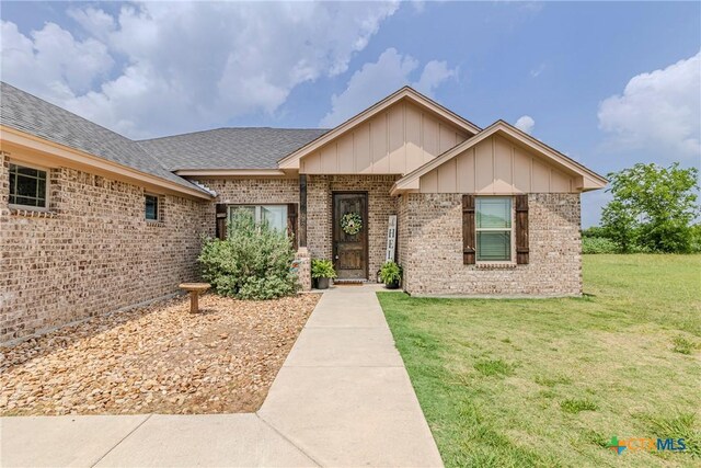 7112 Kc Ranch Ct, Temple, TX 76501 - ranch-style home featuring roof with shingles, board and batten siding, a front lawn, and brick siding