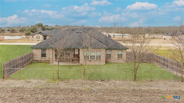 exterior space featuring a shingled roof, a front yard, brick siding, and a fenced backyard