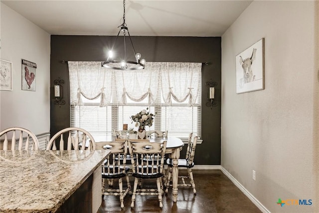 dining area with plenty of natural light, a notable chandelier, finished concrete flooring, and baseboards